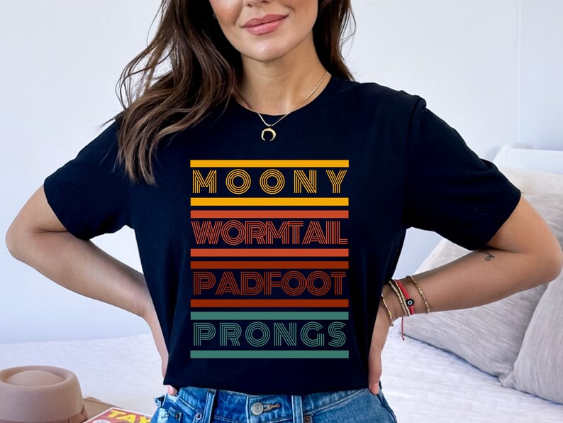 May include: Black t-shirt with a retro-style graphic design featuring the words "Moony", "Wormtail", "Padfoot", and "Prongs" in colorful stripes.