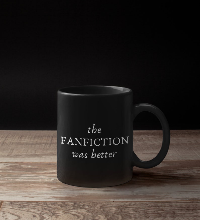 May include: Black ceramic coffee mug with white text that reads "the FANFICTION was better".