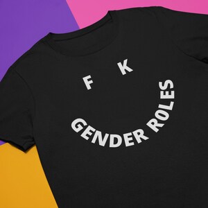 May include: Black t-shirt with white text that reads "F K Gender Roles" in a smiley face shape.