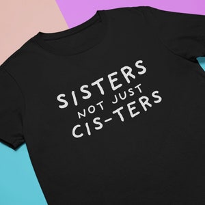 Puede incluir: Camiseta negra con texto blanco que dice "Sisters not just cis-ters".