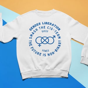 Op de afbeelding: Witte trui met een blauwe grafische print die "Gender Liberation Smash the Cis-Term Queer Power The Future is Non-Binary" zegt. De grafiek bevat ook een gestileerd symbool van een vrouwelijk en mannelijk symbool dat met elkaar verweven is.