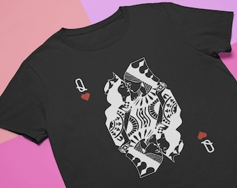 May include: Black t-shirt with a white graphic of two queens of hearts kissing. The graphic is surrounded by a black outline and the text "Q of Hearts" is on either side of the graphic.