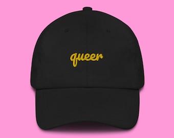 May include: A black baseball cap with a gold embroidered word "queer" on the front.