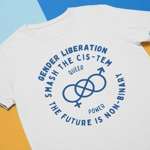 Peut inclure: T-shirt blanc avec un graphique circulaire bleu qui dit "Gender Liberation Smash the Cis-Tem Queer The Future is Non-Binary Power" avec un symbole de signes de genre masculin et féminin qui se chevauchent.