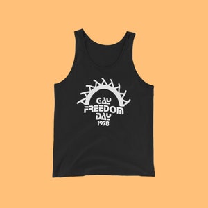 May include: Black tank top with a white graphic of a sun with the text "Gay Freedom Day 1978" printed on the front.