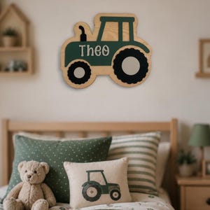 Puede incluir: Una decoración de pared de madera con forma de tractor, que presenta un borde de madera natural, un cuerpo de color verde oscuro y ruedas negras. El nombre Theo está escrito en letras blancas en relieve en el lateral del tractor. Diseño plano.