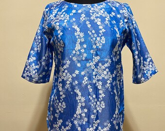 Puede incluir: Una blusa de estampado floral azul y blanco con cuello redondo y mangas tres cuartos.