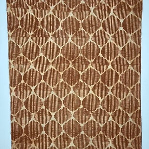 Könnte beinhalten: Ein gewebtes Textil in Braun und Weiß mit einem geometrischen Muster. Das Textil hat einen Fransenrand.