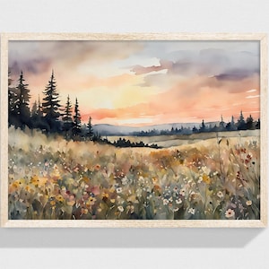 Puede incluir: Impresión artística de paisaje en acuarela que representa una puesta de sol sobre un campo de flores silvestres y hierba alta. La obra de arte incluye un bosque de árboles de hoja perenne en el lado izquierdo y un cielo colorido con tonos naranja y gris. La impresión está en un marco de madera clara.