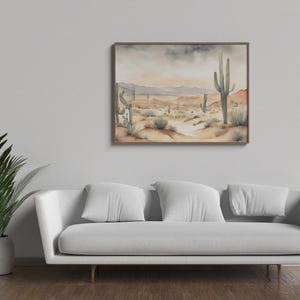 Nestled above a white cotton sofa and next to a lush green palm, the beautiful watercolor desert landscape illustration becomes the soul of this cozy living room