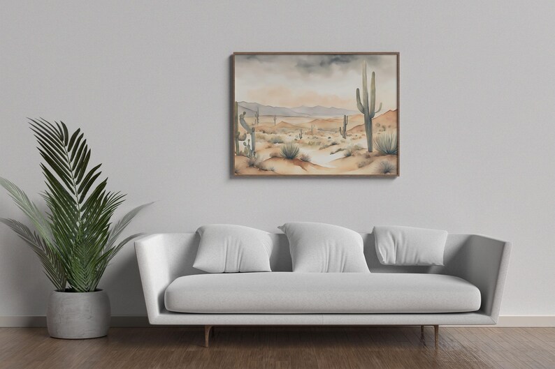 Nestled above a white cotton sofa and next to a lush green palm, the beautiful watercolor desert landscape illustration becomes the soul of this cozy living room