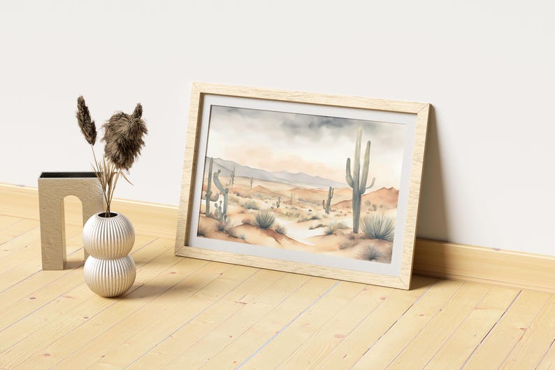 Laid gently on an oak-textured floor, the beautiful watercolor desert landscape piece rests beside a decorative plastic vase adorned with ornamental feathers