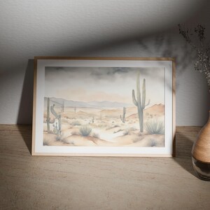 Gracing the top of a minimal wooden table, the beautiful watercolor desert landscape painting tells a story of desert calm, complete with clusters of cactus