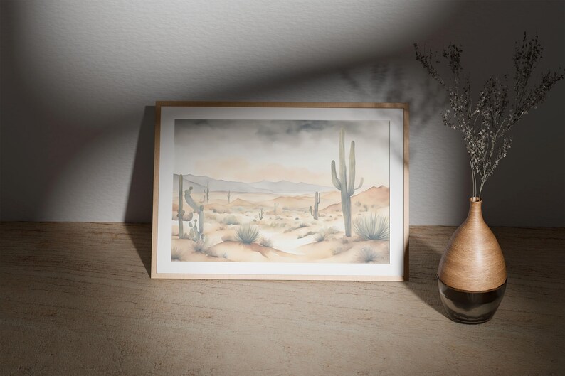 Gracing the top of a minimal wooden table, the beautiful watercolor desert landscape painting tells a story of desert calm, complete with clusters of cactus