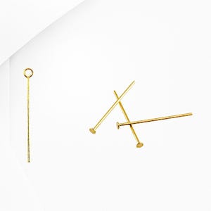 May include: Gold head pins with a loop on one end and a flat head on the other. These pins are used for jewelry making and crafting.