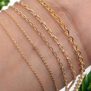 Puede incluir: Primer plano de varios collares de cadena dorados con diferentes estilos de eslabones. Las cadenas se muestran sobre un fondo de tono de piel, mostrando los diferentes diseños y texturas de las joyas. Las cadenas son probablemente para collares o pulseras.