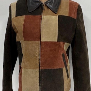 May include: A patchwork jacket featuring a color-blocked design in shades of dark brown, tan, and rust. The garment includes a solid dark brown leather collar, long sleeves, a full-length front zipper closure, and two vertical side pockets.