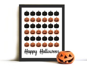 May include: A black framed print with a white background and a pattern of black and orange jack-o'-lanterns. The text "Happy Halloween" is printed at the bottom of the print.
