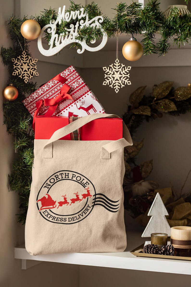 May include: A beige canvas tote bag with the words "North Pole Express Delivery" printed on it, filled with wrapped gifts. The gifts are wrapped in red and patterned paper. Christmas decorations, including ornaments and snowflakes, are in the background.