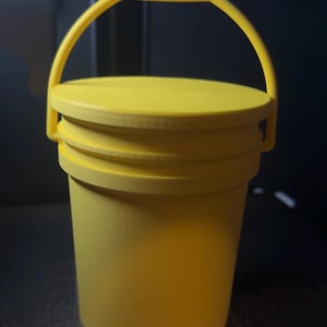May include: A vibrant yellow bucket with a lid and a handle. The bucket is cylindrical with a lid featuring concentric rings. The handle is arched. The overall design is simple and functional. The bucket is suitable for various uses.