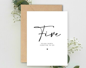 May include: A white card with black text that reads "Five years down, forever to go" with a small heart symbol below the text.