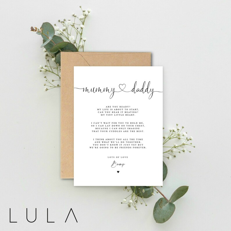 May include: A white card with black text that reads "mummy daddy" with a heart symbol between the words. The card has a message about a new baby and the love between a parent and child. The card is on a brown envelope with green leaves.