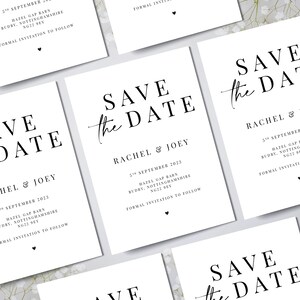 May include: White rectangular cards with the text "SAVE the DATE" in a black, elegant font. The cards also include the names "RACHEL & JOEY", date, location, and a small heart. Wedding stationery.