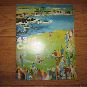 May include: An artistic magazine cover with the text "43rd Crosby" in white. The cover features a colorful painting of a golf course scene with people, water, and a coastal landscape. The artwork has a vintage feel.