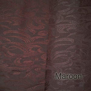 May include: A close-up of a maroon fabric with a swirling pattern. The fabric has a subtle sheen and a soft texture.