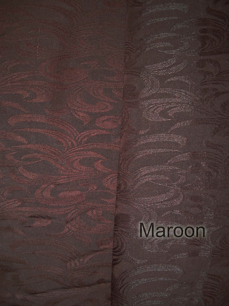 May include: A close-up of a maroon fabric with a swirling pattern. The fabric has a subtle sheen and a soft texture.