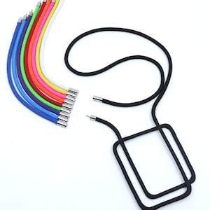 Puede incluir: Un juego de cordones para teléfono de colores con cierres de metal plateado. Los cordones están dispuestos en forma de arcoíris. También se muestra un cordón para teléfono negro con un soporte rectangular para teléfono.