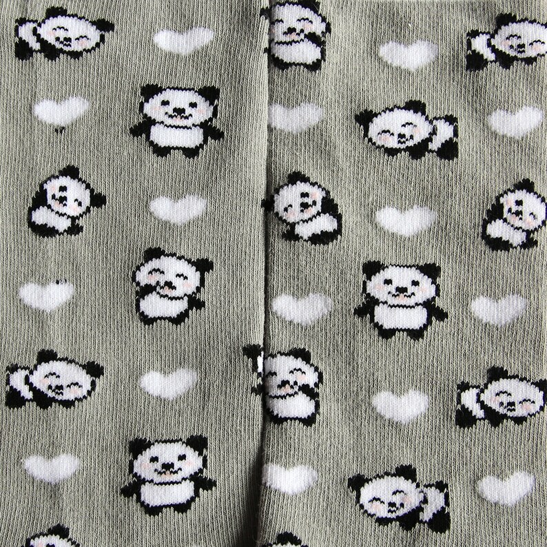 K&ouml;nnte beinhalten: Graue Strumpfhosen mit einem sich wiederholenden Muster aus wei&szlig;en Herzen und schwarz-wei&szlig;en Pandab&auml;ren. Die Pandas l&auml;cheln und haben schwarze Augen.