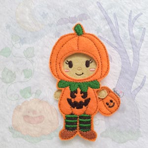 May include: A felt appliqué of a child dressed as a pumpkin for Halloween. The child is wearing a pumpkin costume with a jack-o'-lantern face and holding a small pumpkin bucket.