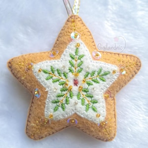 May include: A felt star-shaped ornament with a gingerbread cookie design. The star is decorated with green and gold embroidery, white beads, and iridescent sequins.