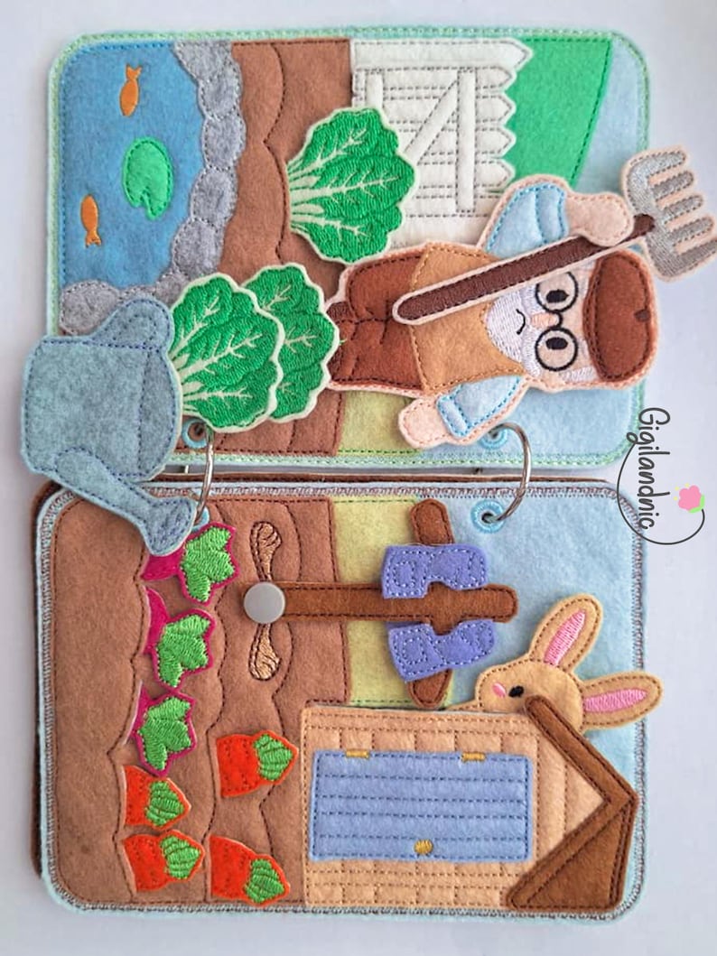 May include: A felt quiet book featuring two pages with farm scenes. The top page shows a gardener with a pitchfork, a pond, and a watering can. The bottom page depicts a carrot patch, a rabbit, and a small house. The text Gigilandnic is visible.