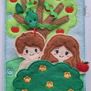 May include: A rectangular felt craft panel featuring a light blue background with a brown tree, green foliage, and red apples. Two figures with brown hair are positioned behind a dark green bush with yellow flowers. A green snake is on the tree.