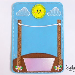 Puede incluir: Un conjunto de juego de fieltro con una cuerda de ropa marrón, un cubo rosa y un sol amarillo sonriente con nubes blancas. El conjunto es perfecto para juegos de simulación y para enseñar a los niños sobre la colada.