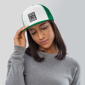 Puede incluir: Una gorra de camionero blanca y verde con un gráfico en blanco y negro que dice "TULSA 1921 OKLAHOMA".