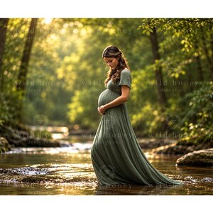 May include: A floor-length olive green maternity dress with short sleeves and a fitted bodice that flows into a long, gathered skirt. The fabric features a subtle ribbed texture, and the garment is designed to accommodate a pregnant belly.