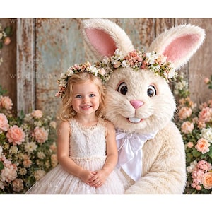 May include: A young child with blonde hair wearing a white lace dress and a floral crown sits next to a large, plush, cream-colored rabbit mascot. The rabbit features long ears with pink inner lining, a pink nose, and a white bow tie around its neck.