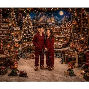 May include: Two children stand in a snowy village scene wearing matching red and black plaid pajamas. The background features a festive North Pole setting with elves, a Christmas tree, a toy workshop, and a chalkboard sign reading Today's Plan.