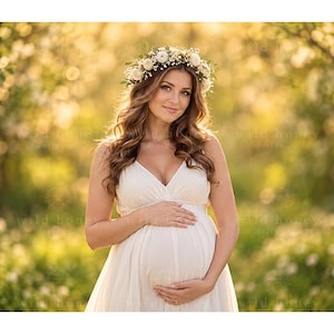 Può includere: Un abito premaman bianco senza maniche con scollo a V e gonna fluida, indossato con una corona di fiori composta da piccoli fiori bianchi e fogliame verde. Il capo presenta un corpetto aderente che si trasforma in una gonna morbida e drappeggiata.