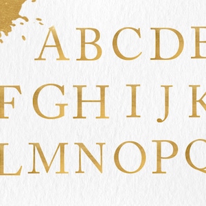 Op de afbeelding: Gouden folie letters van het alfabet, A tot en met Q, op een witte achtergrond.