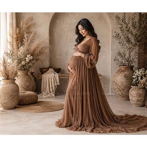 May include: A floor-length maternity gown in a solid brown hue, featuring a deep V-neckline, long sheer bishop sleeves with gathered cuffs, and a voluminous, layered tulle skirt that extends into a train, designed for a pregnant silhouette.