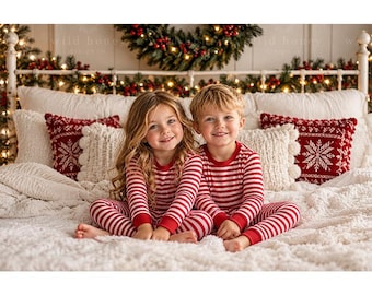 May include: Two children sitting on a bed wearing matching long-sleeved pajamas with horizontal red and white stripes. The pajamas feature a crew neckline and fitted cuffs at the wrists and ankles. The bed is covered with a white textured blanket.