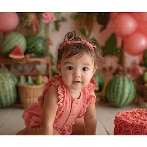 May include: A baby girl in a pink romper and headband sits in a watermelon-themed setting. Watermelons, balloons, and a cake with rose-shaped frosting are visible. The background includes floral decorations.