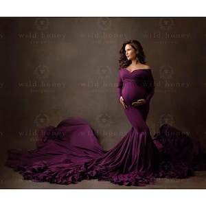 Könnte beinhalten: Ein langes, fließendes Umstandskleid mit freier Schulter in tiefem Lila. Das Kleid hat lange Ärmel, ein eng anliegendes Oberteil und einen Rock im Meerjungfrauen-Stil mit einer dramatischen Schleppe. Der Stoff fällt elegant und sorgt für einen raffinierten Look.