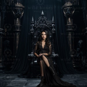 Peut inclure: Une femme vêtue d'une robe en dentelle noire est assise sur un trône orné sombre dans une pièce faiblement éclairée. Le trône est en métal et possède un dossier et des accoudoirs hauts. La femme a les cheveux longs et noirs et regarde directement la caméra.