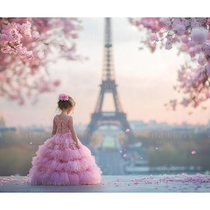 Könnte beinhalten: Ein junges Mädchen in einem rosa Tüllkleid mit Spitzendetails steht vor dem Eiffelturm. Im Hintergrund befinden sich rosa Kirschblüten.