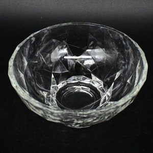 May include: A clear glass bowl with a faceted design. The bowl is empty and has a round shape.